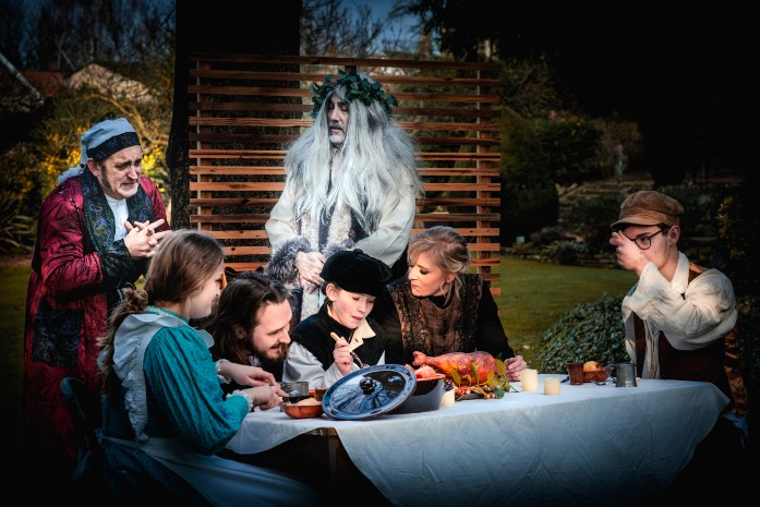 The Ghost of Christmas Present showing Scrooge the Cratchit family Christmas dinner