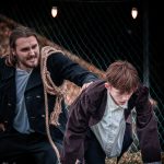 Bill Sykes pushing Oliver Twist across a roof with a rope over his shoulder